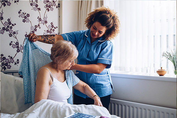 Female home caregiver talking with senior woman, sitting in living room and listening to her carefully.